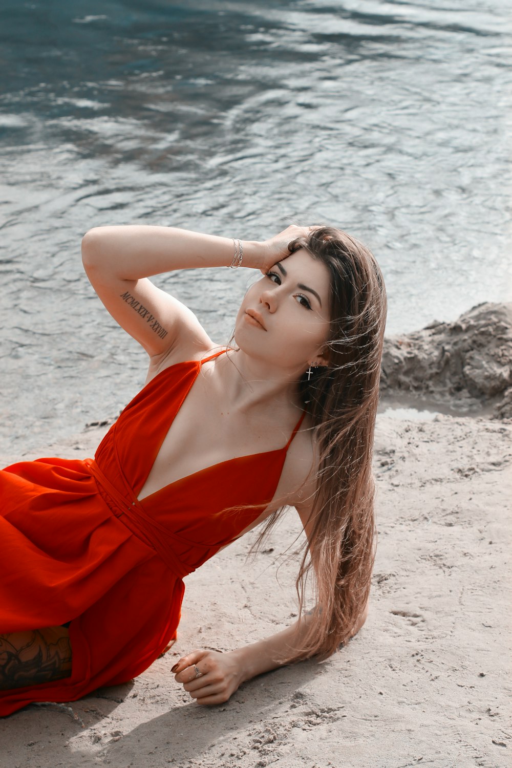 Femme en robe rouge à bretelles spaghetti debout sur la plage pendant la journée