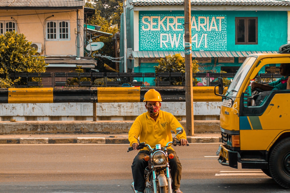 man in yellow hard hat riding motorcycle during daytime