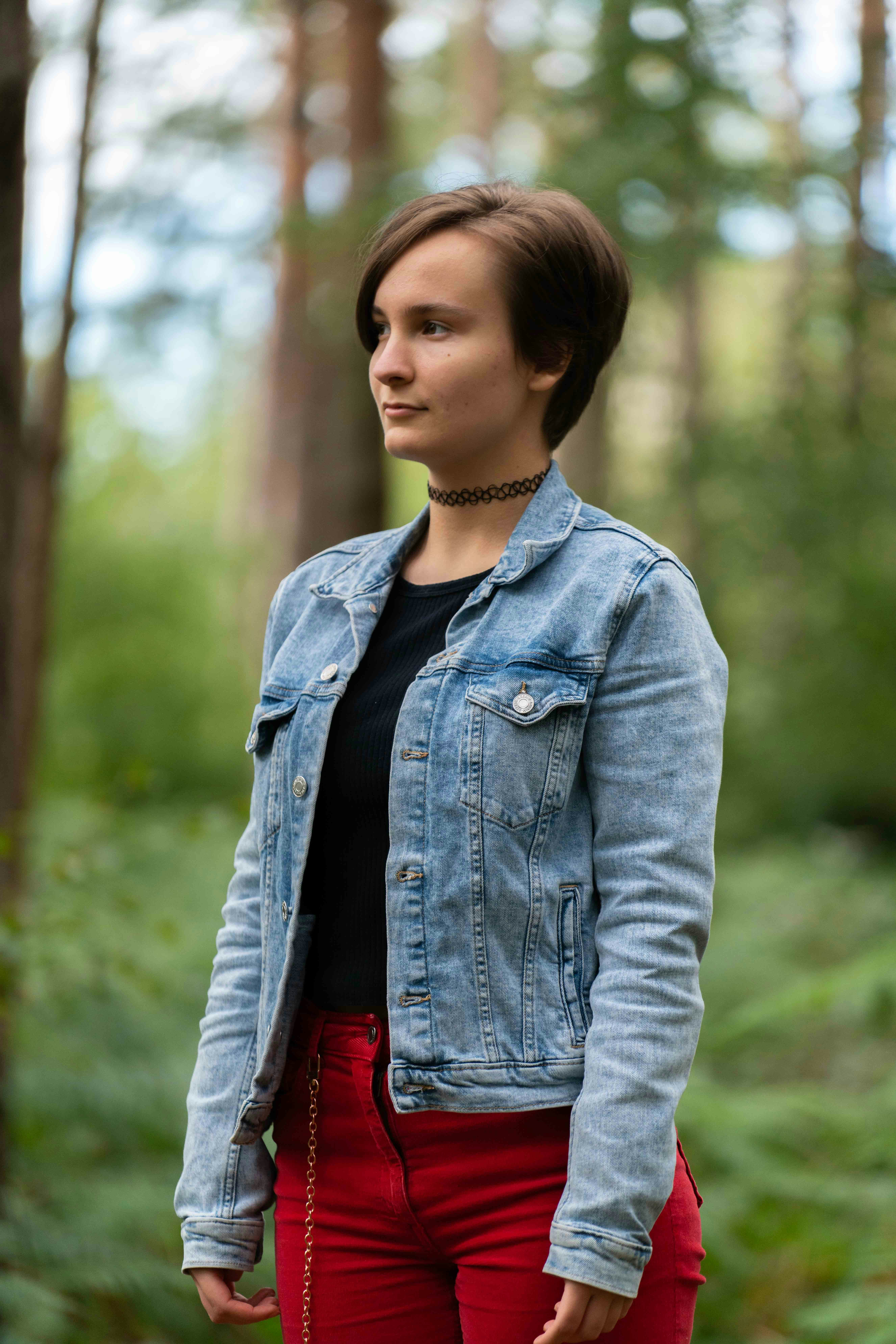 Woman in blue denim jacket standing near green trees during daytime ...