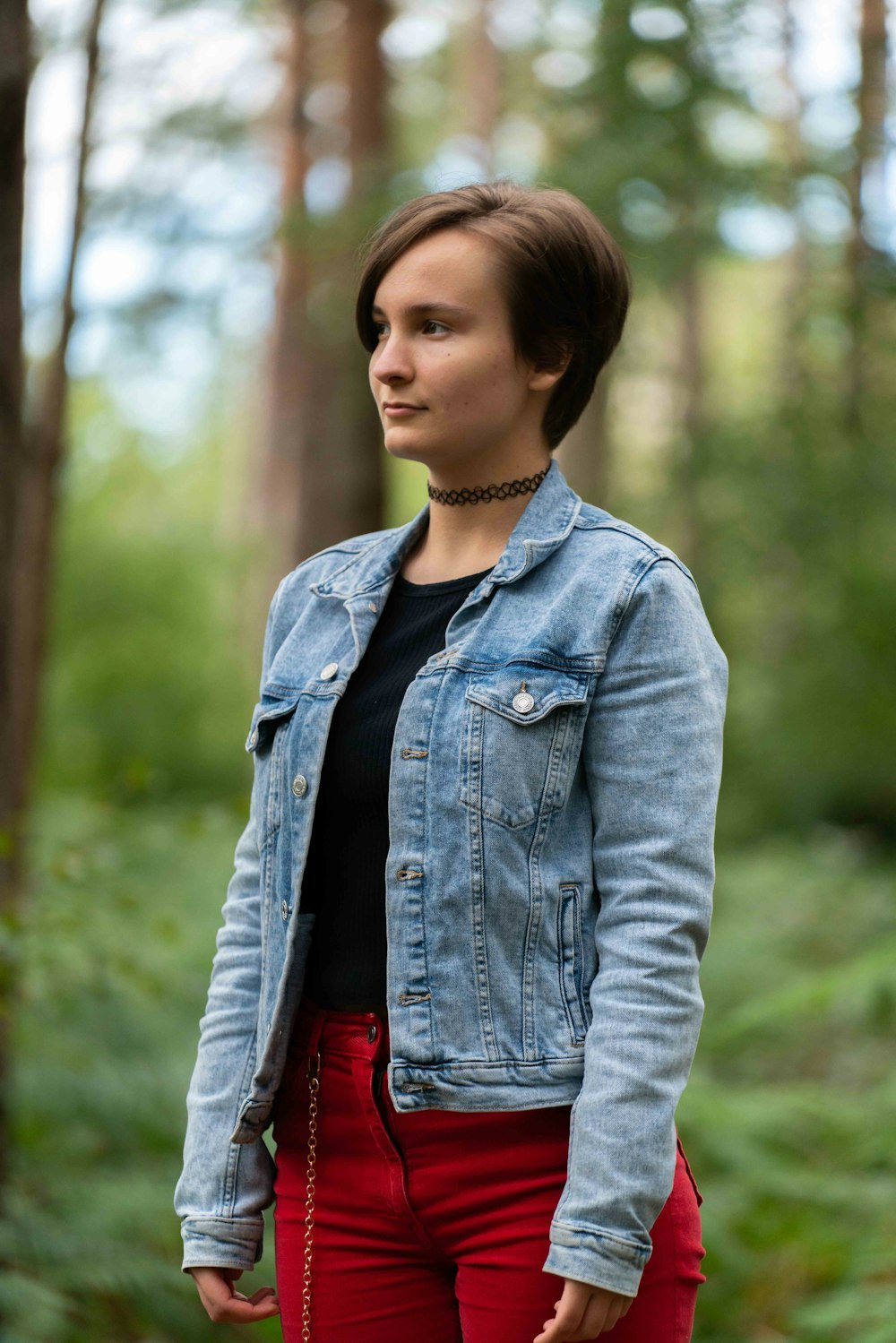 woman in blue denim jacket standing near green trees during daytime