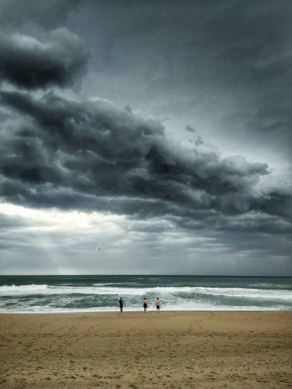 persone sulla spiaggia sotto il cielo nuvoloso durante il giorno