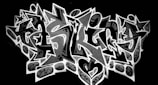 Bold and intricate graffiti design with sharp, angular letters and star motifs, set against a dark background. The central lettering is highlighted by a contrasting outline and embellished with patterns and symbols.