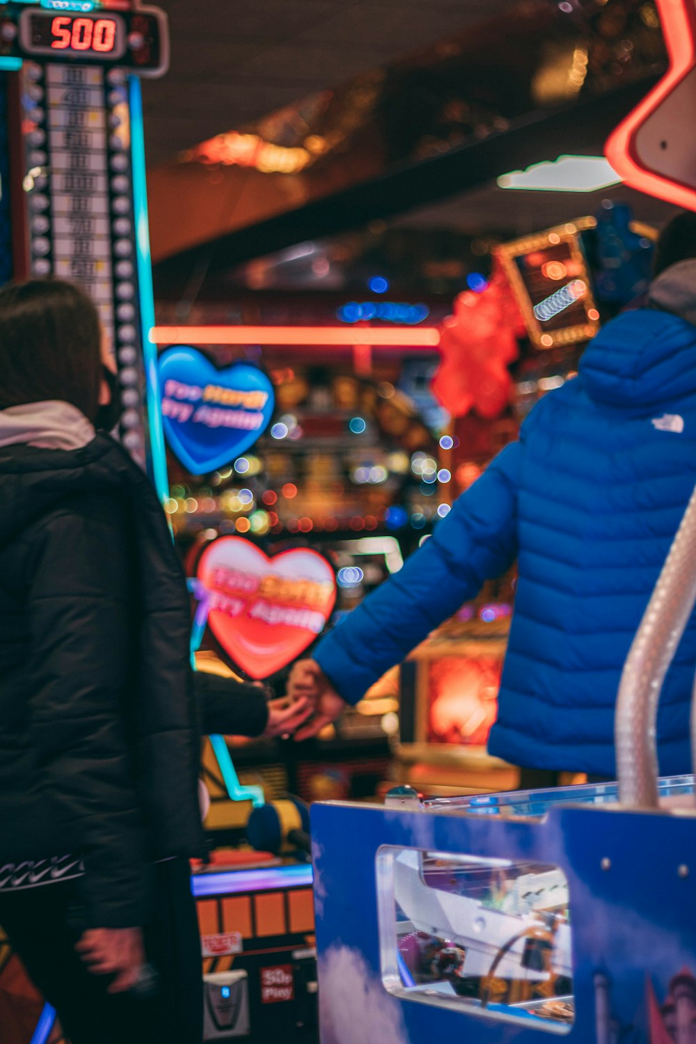 woman in blue jacket standing near arcade machine