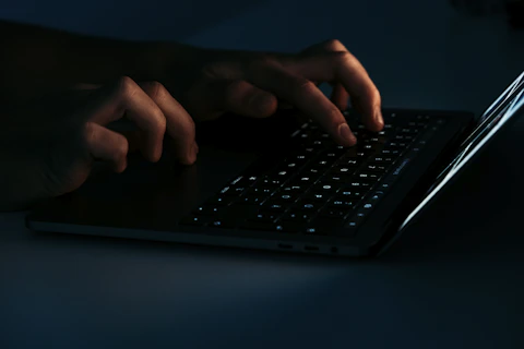 Close-up of hands typing on a laptop keyboard in a bright workspace.