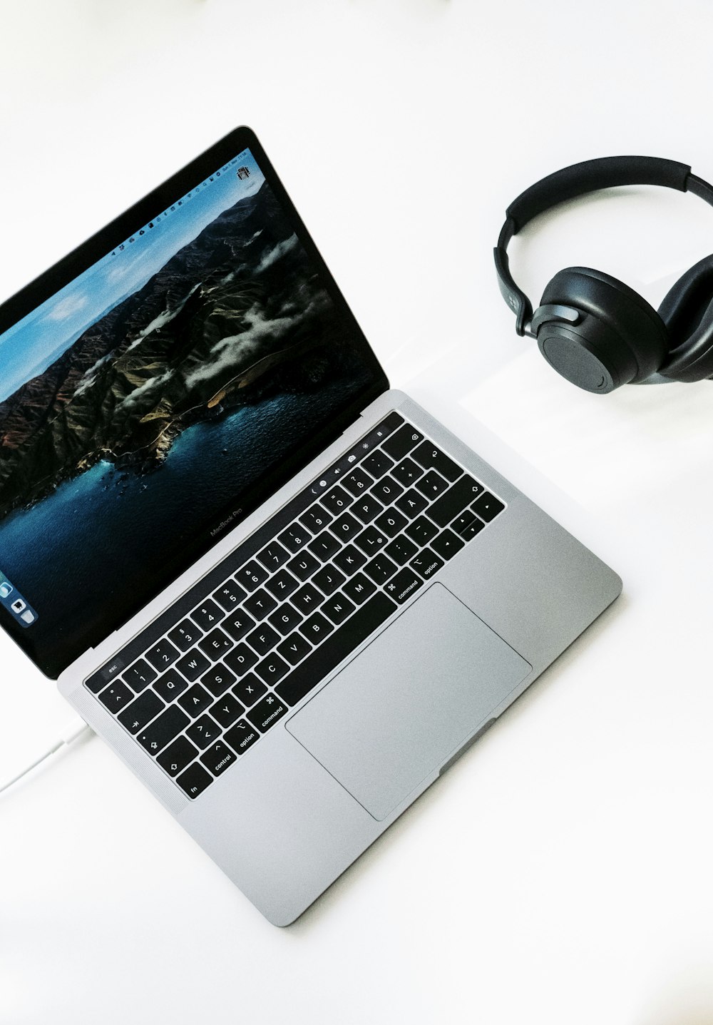 macbook pro ao lado de fones de ouvido pretos
