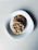 Close-up shot of a single, perfectly baked crumzi cookie on a minimalist white plate with soft shadows.