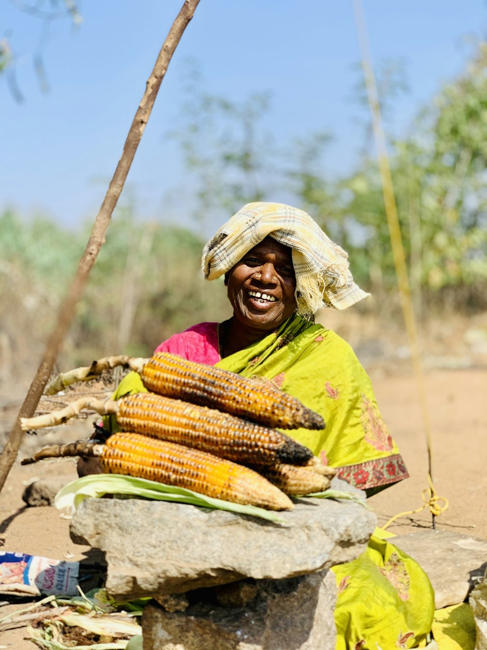 Mujer con hiyab amarillo y verde sosteniendo maíz