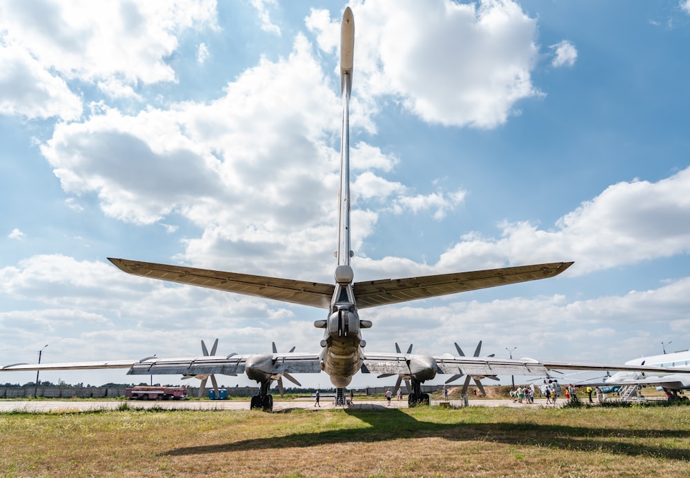 gray fighter plane on green grass field under blue and white sunny cloudy sky during daytime