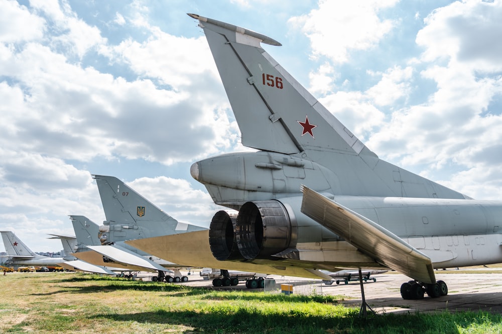 gray fighter plane on green grass field under white clouds during daytime