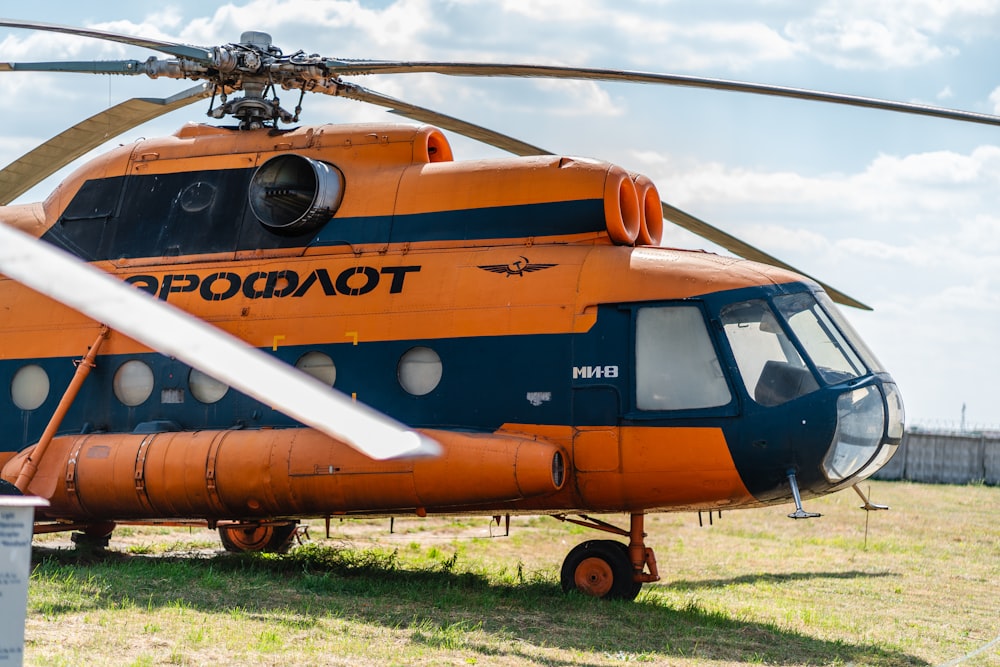 orange and white helicopter on green grass field during daytime