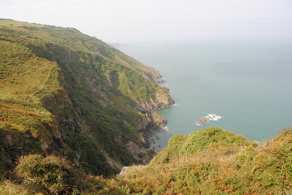 green and brown mountain beside sea during daytime