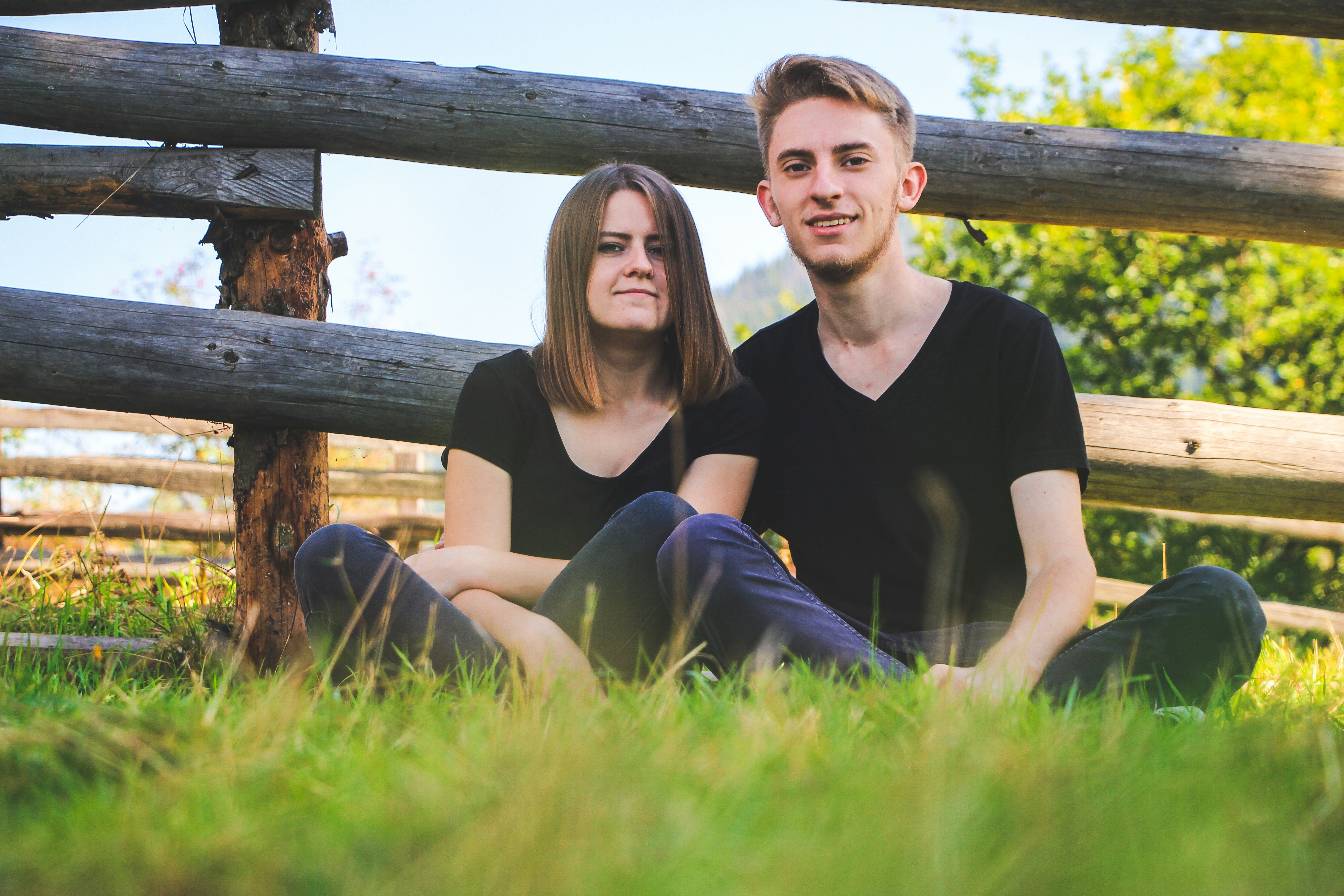 Young couple sitting on a grass near the fence
