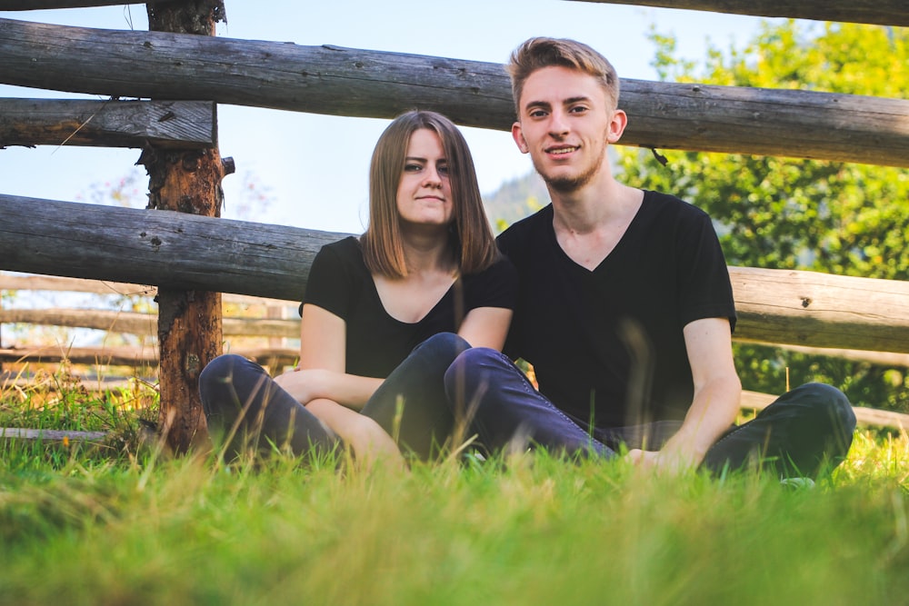 homme et femme assis sur le champ d’herbe verte pendant la journée
