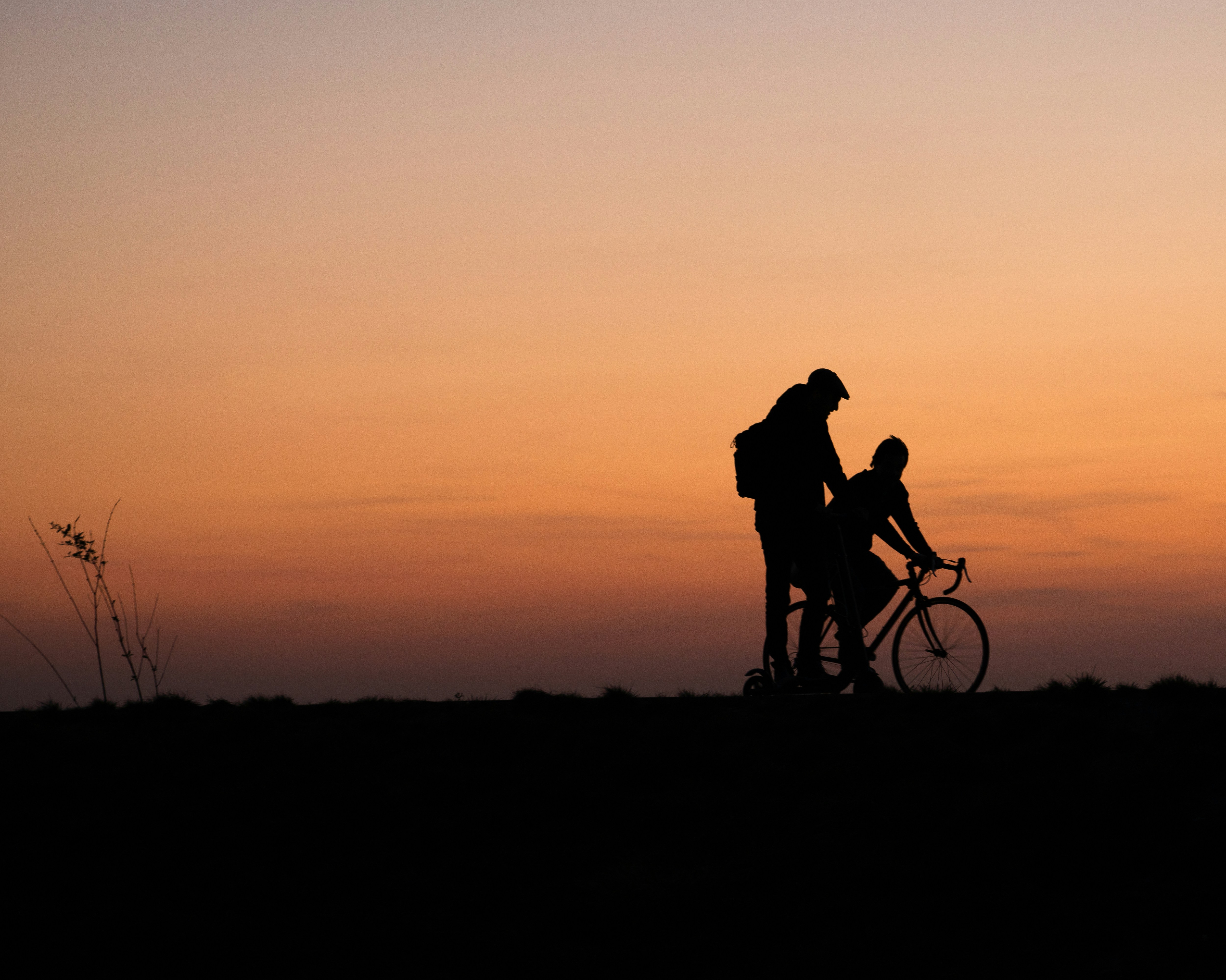 silhouette of man and woman riding bicycle during sunset