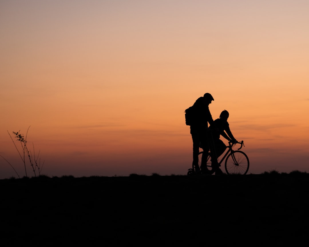 silhouette of man and woman riding bicycle during sunset