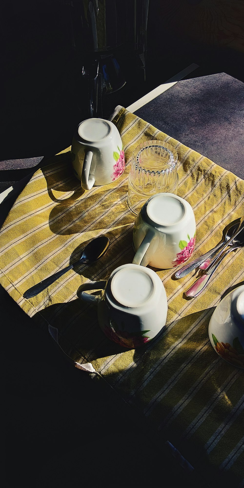 weißer Keramikbecher neben Edelstahlgabel und Messer auf braunem Tisch