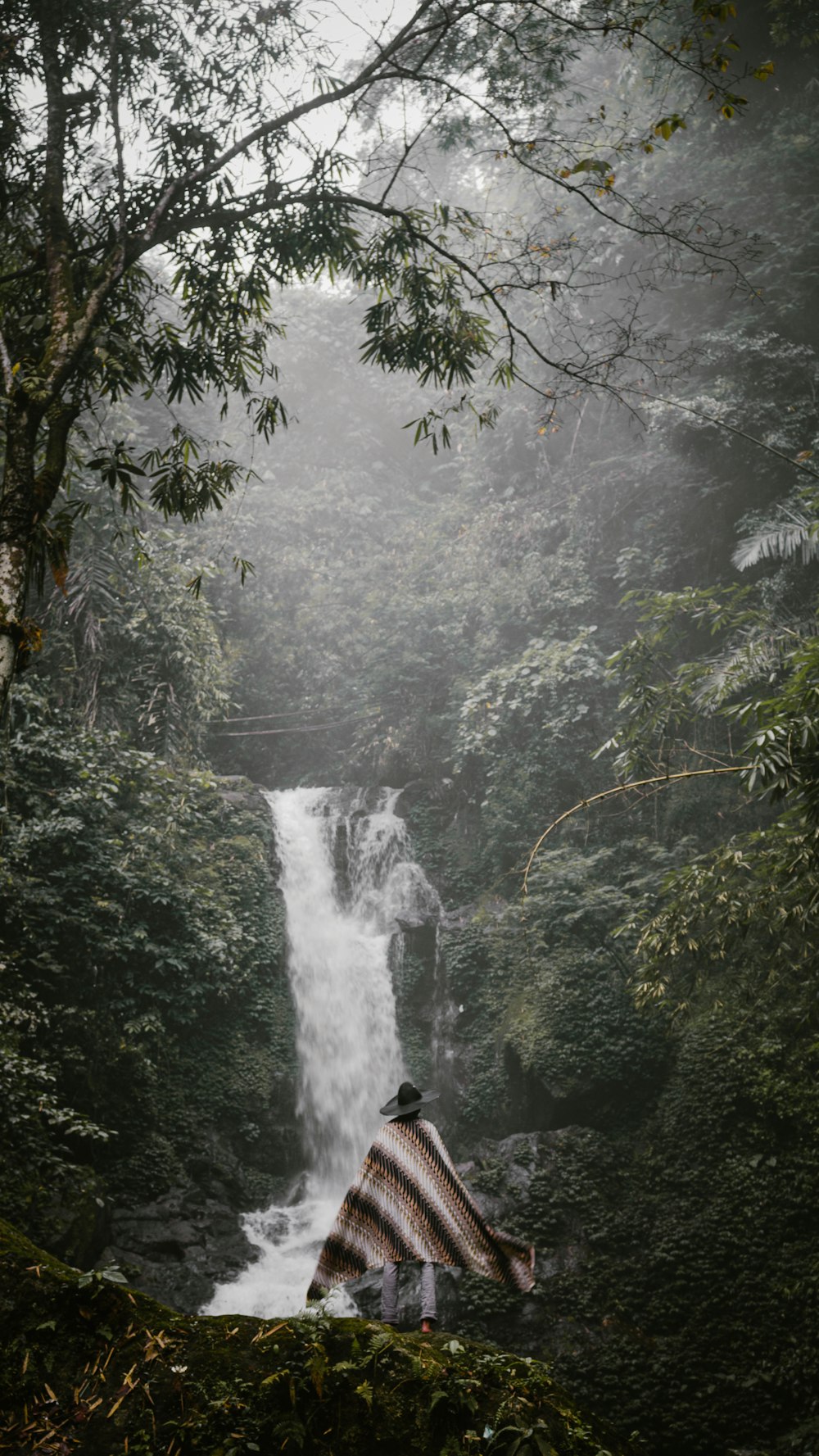person in black jacket standing in front of waterfalls