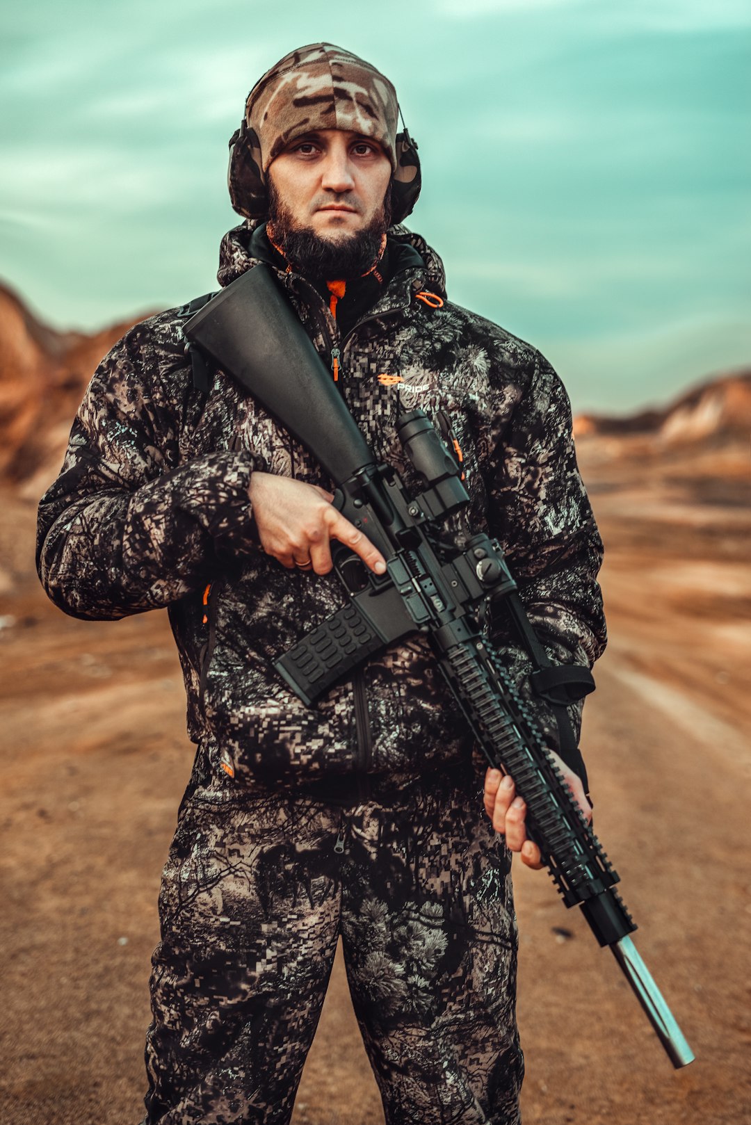 man in black and gray camouflage jacket holding black rifle