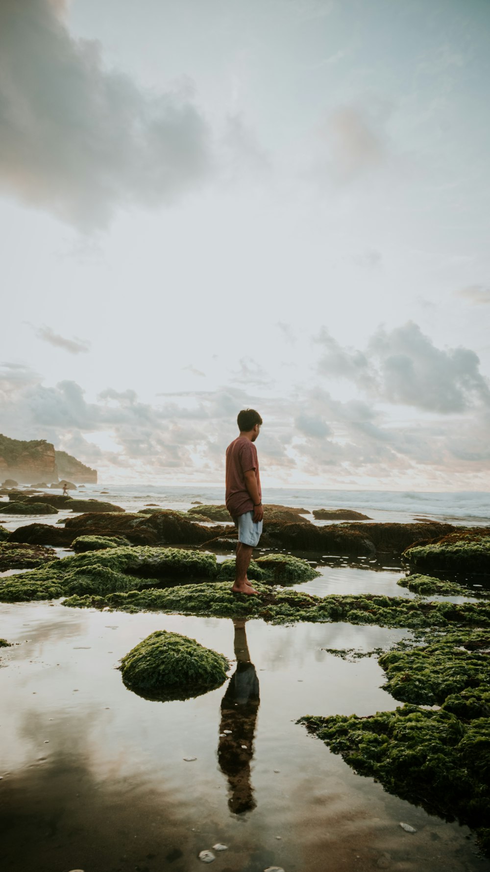 woman in white tank top and blue denim shorts standing on green moss covered rock near near near near near