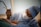 A surgeon wearing a blue surgical gown, cap, mask, and gloves is intently focused on a procedure. They are holding a surgical instrument while performing surgery. The scene is well-lit with a soft, clinical ambiance.