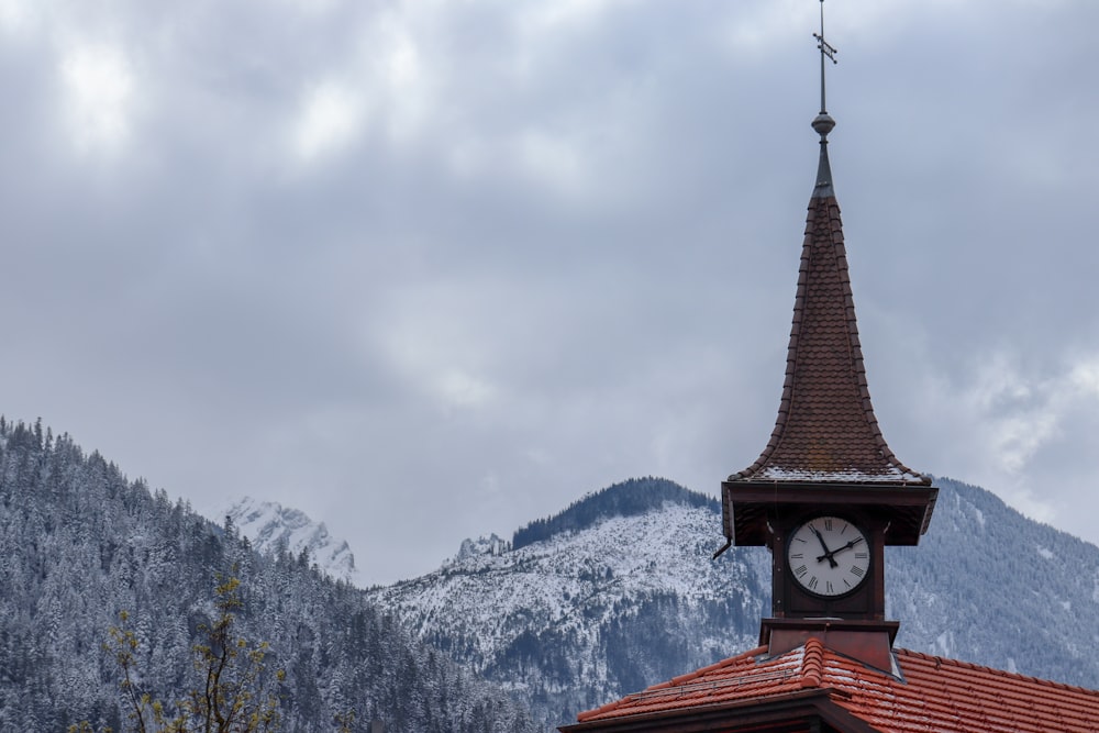 brown and black tower near snow covered mountain during daytime