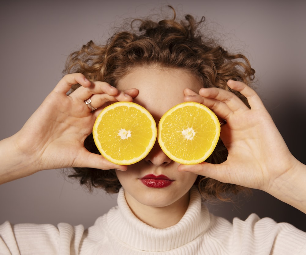 mulher que segura a fruta laranja fatiada