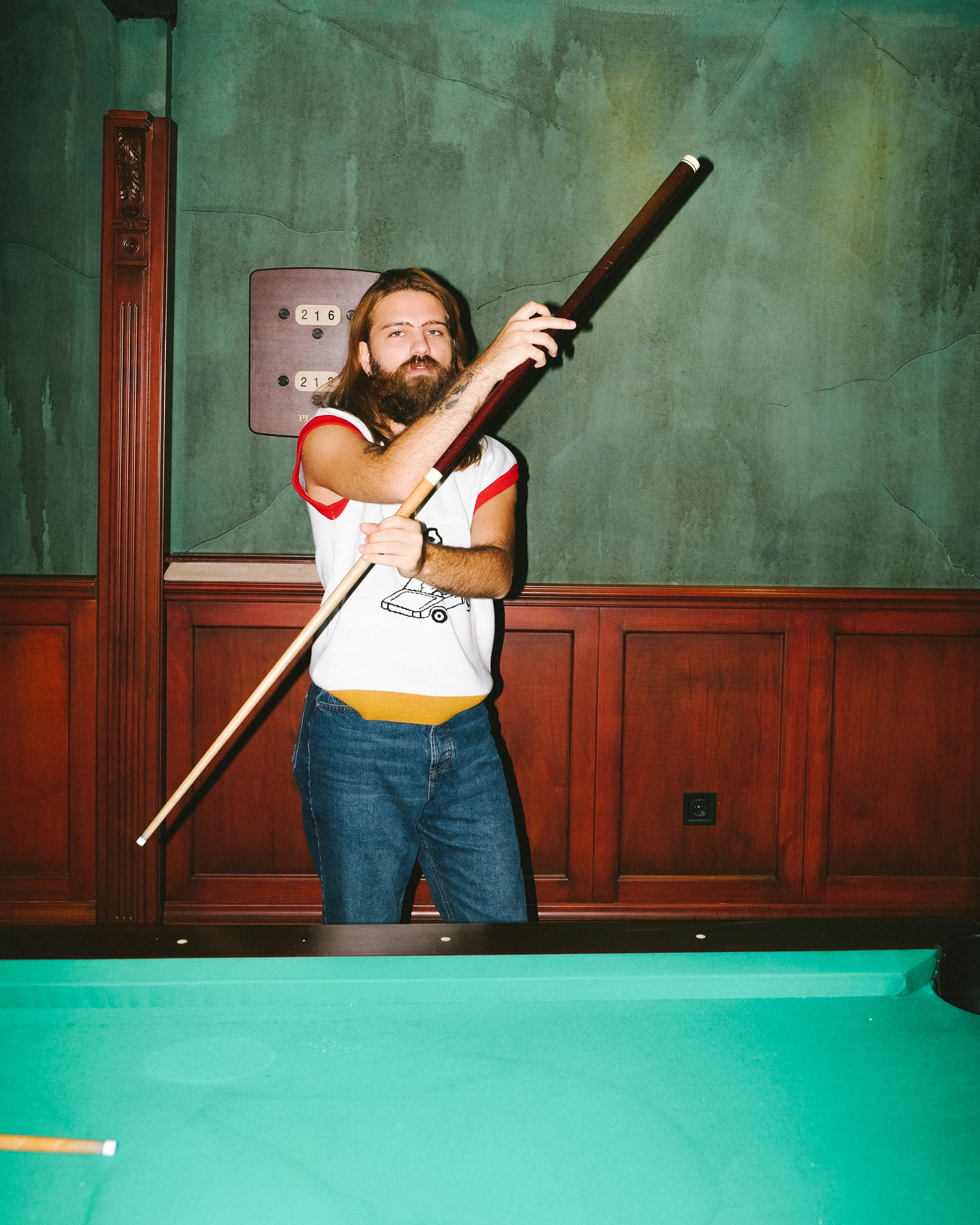 woman in white shirt and blue denim jeans holding brown wooden stick