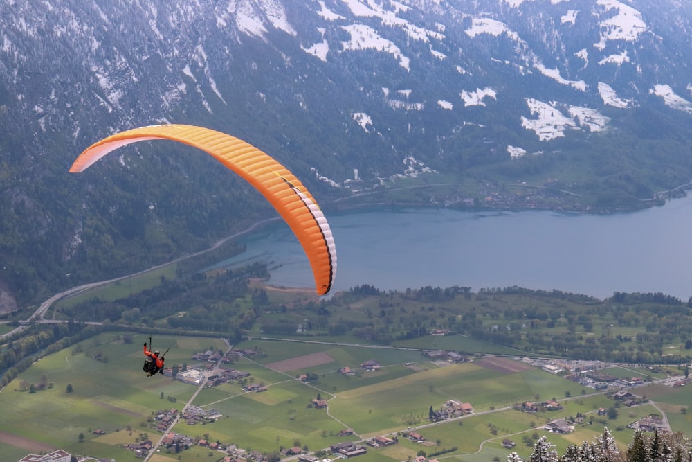 people riding parachute over green mountains during daytime