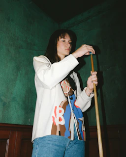 A hand chalking the tip of a billiard cue with blue chalk