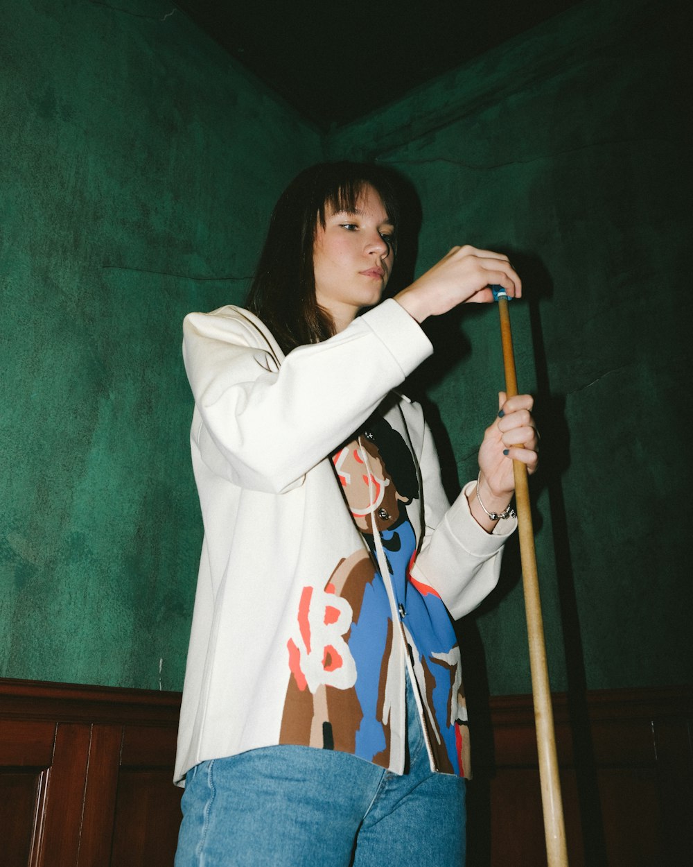 woman in white long sleeve shirt holding brown wooden stick