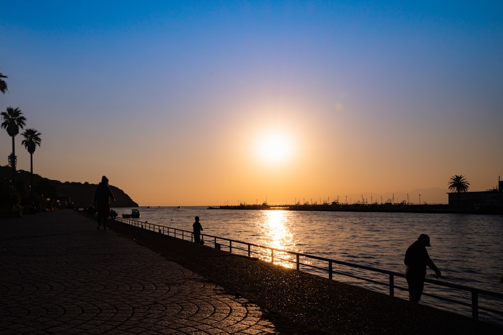 silhouette of people walking on beach during sunset