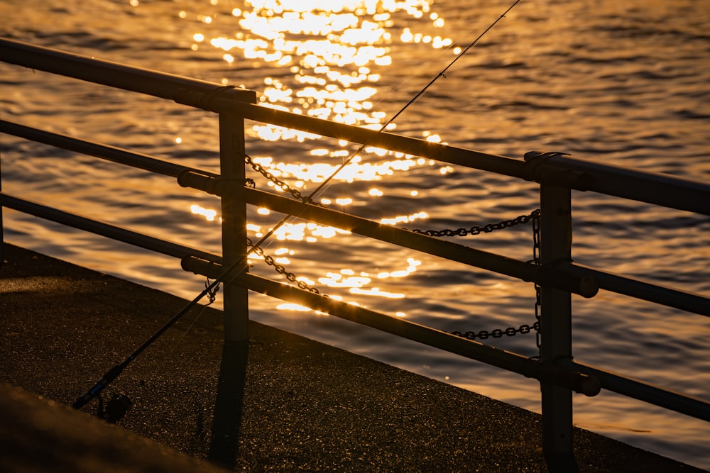 brown wooden fence near body of water during sunset