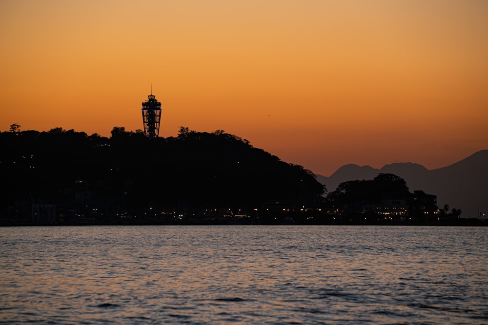 silhouette of mountain and body of water during sunset