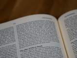 An open book with visible black text on white pages. The text appears to be in English and features a passage from the Old Testament. The focus is on the left-hand page, which includes content relating to commandments and blessings.