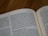 An open book with visible black text on white pages. The text appears to be in English and features a passage from the Old Testament. The focus is on the left-hand page, which includes content relating to commandments and blessings.