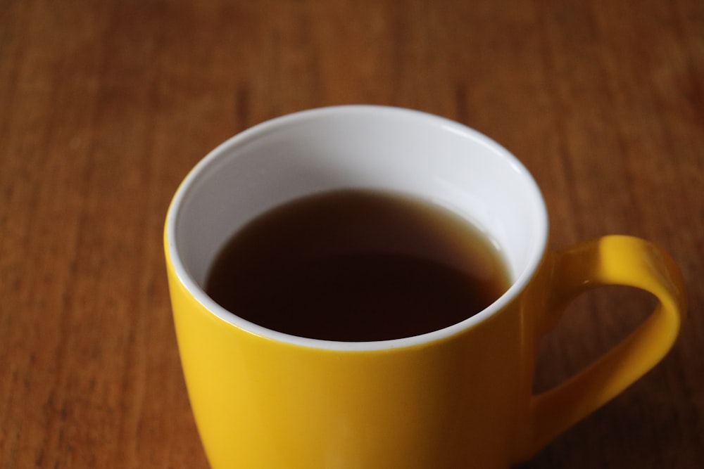 white and yellow ceramic mug on brown wooden table