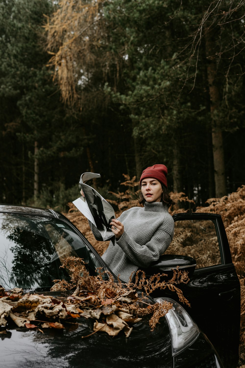 woman in gray sweater sitting on black car