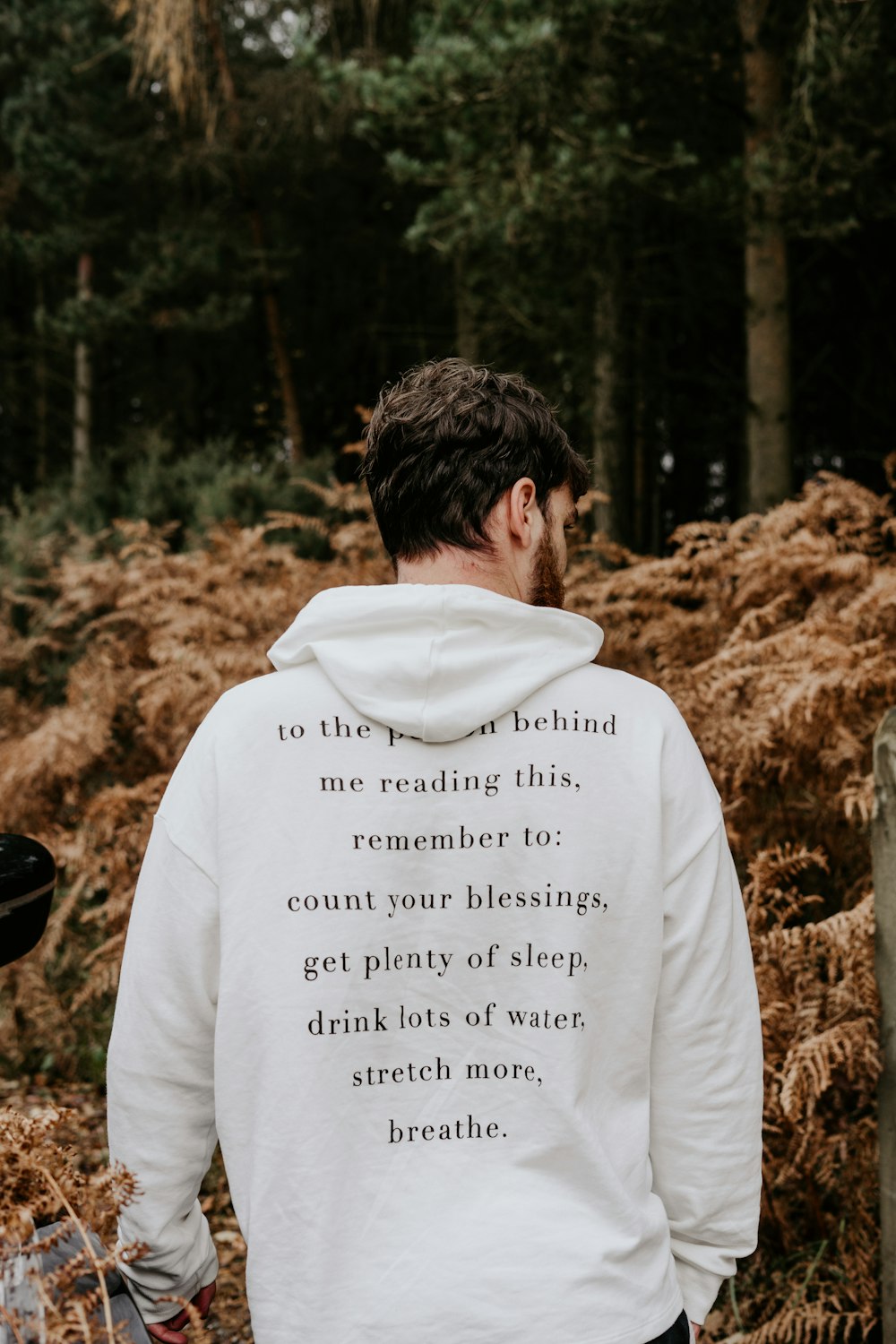 man in white hoodie standing on brown grass field during daytime