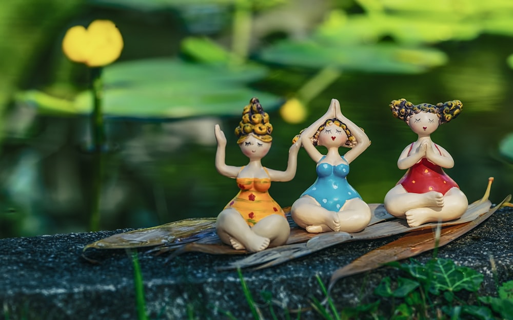three little figurines are sitting on a leaf