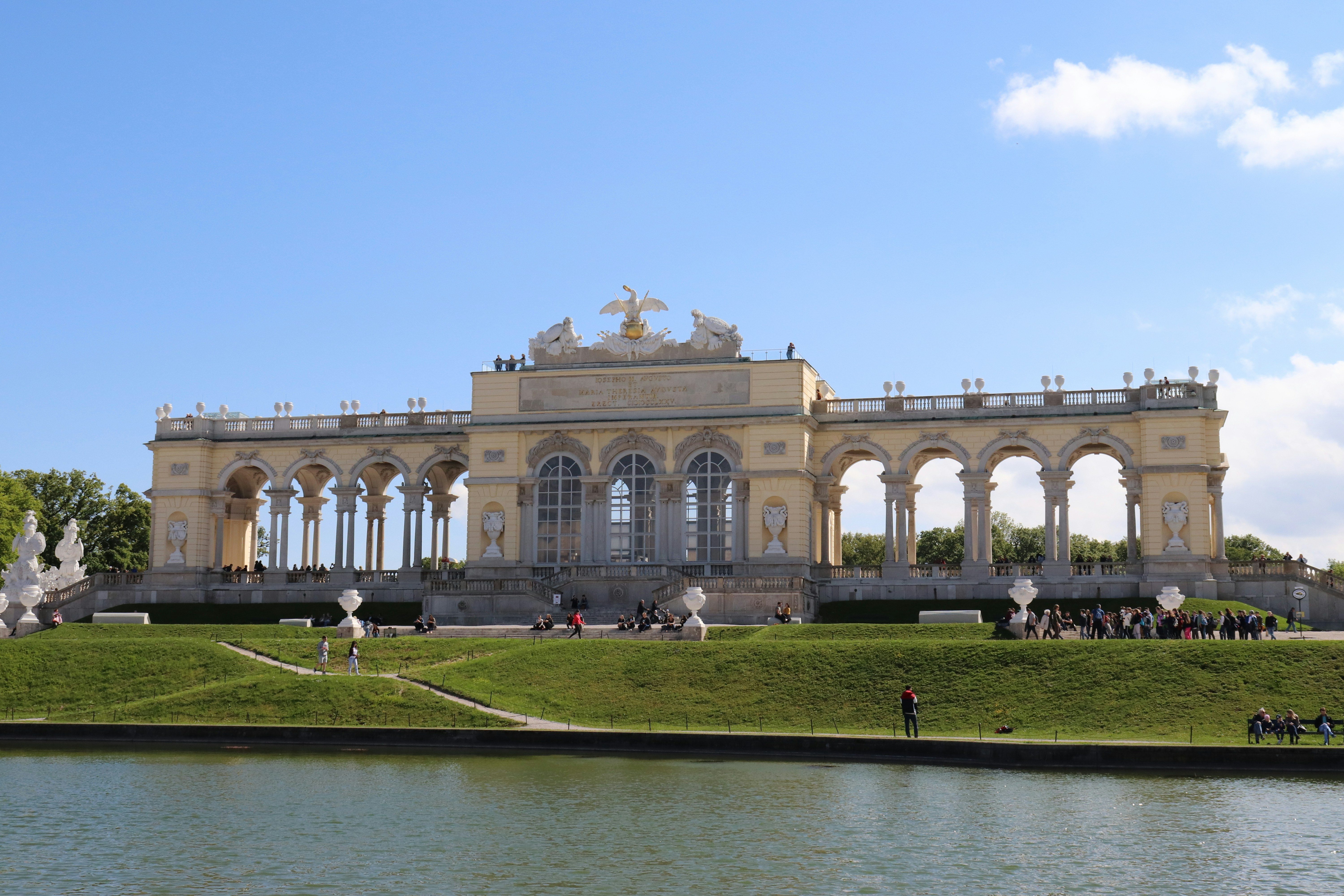 Bâtiment en béton blanc près d’un champ d’herbe verte sous un ciel bleu pendant la journée