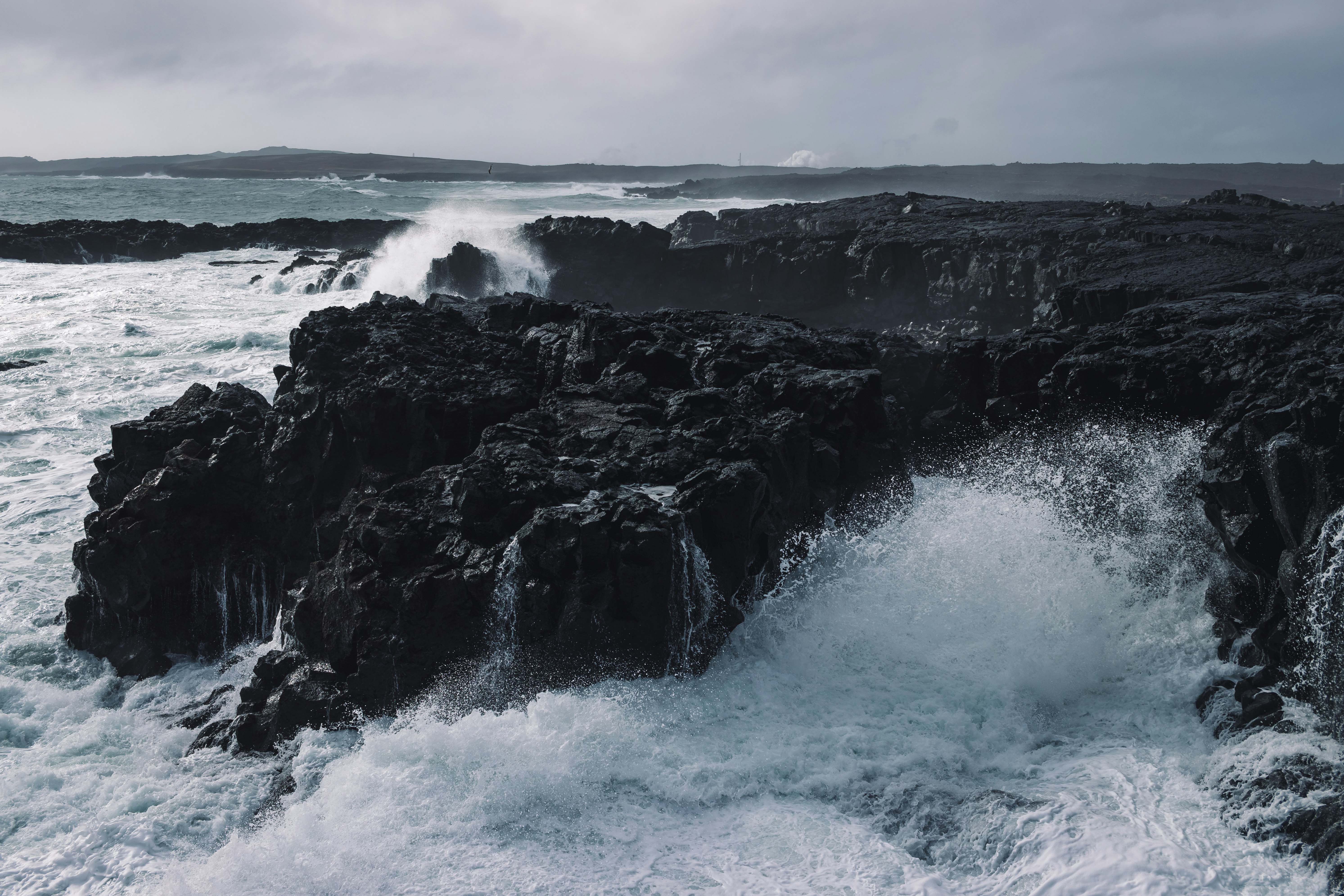 ocean waves crashing on black rock formation during daytime