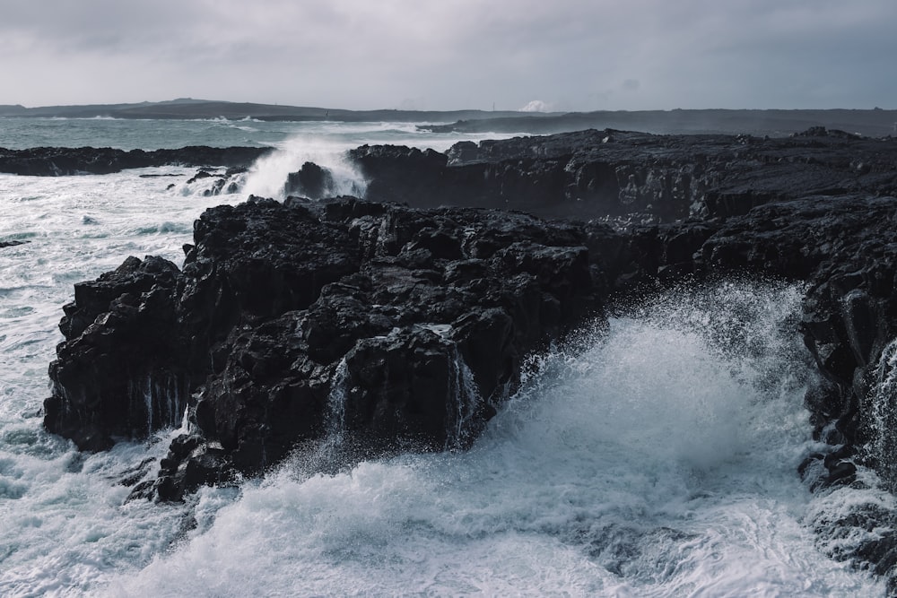 ocean waves crashing on black rock formation during daytime