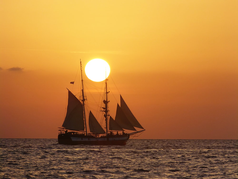 brown sail boat on sea during sunset