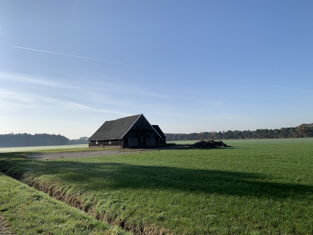 brown house on green grass field under blue sky during daytime