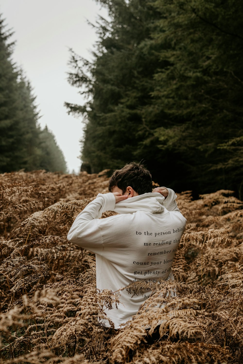 woman in white long sleeve shirt covering her face with brown dried grass