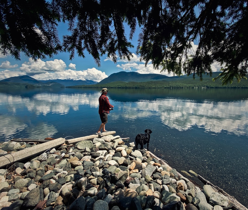 person in red jacket standing near lake during daytime