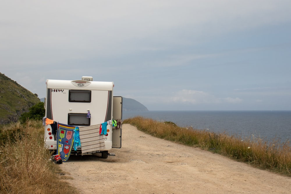 white and gray rv trailer on brown field under white sky during daytime