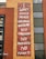A mural with colorful abstract patterns features text calling for world peace, universal healthcare, and the end of oppression, prejudice, and poverty. The mural is located on the side of a brick building, with a no entry traffic sign visible nearby.