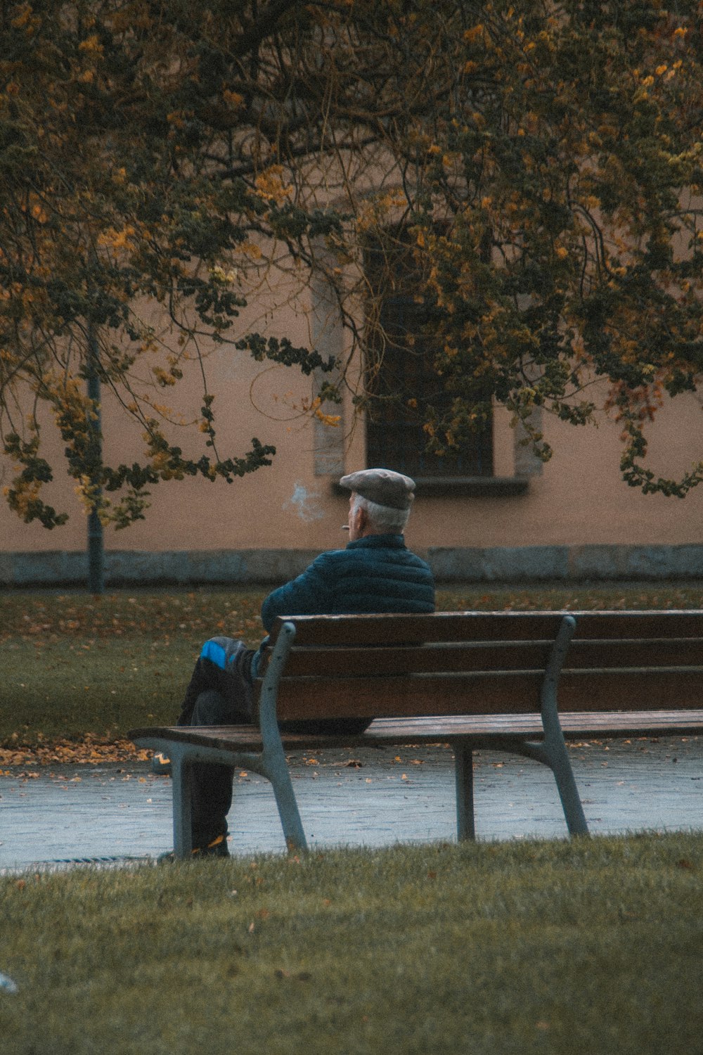 man in blue jacket sitting on brown wooden bench