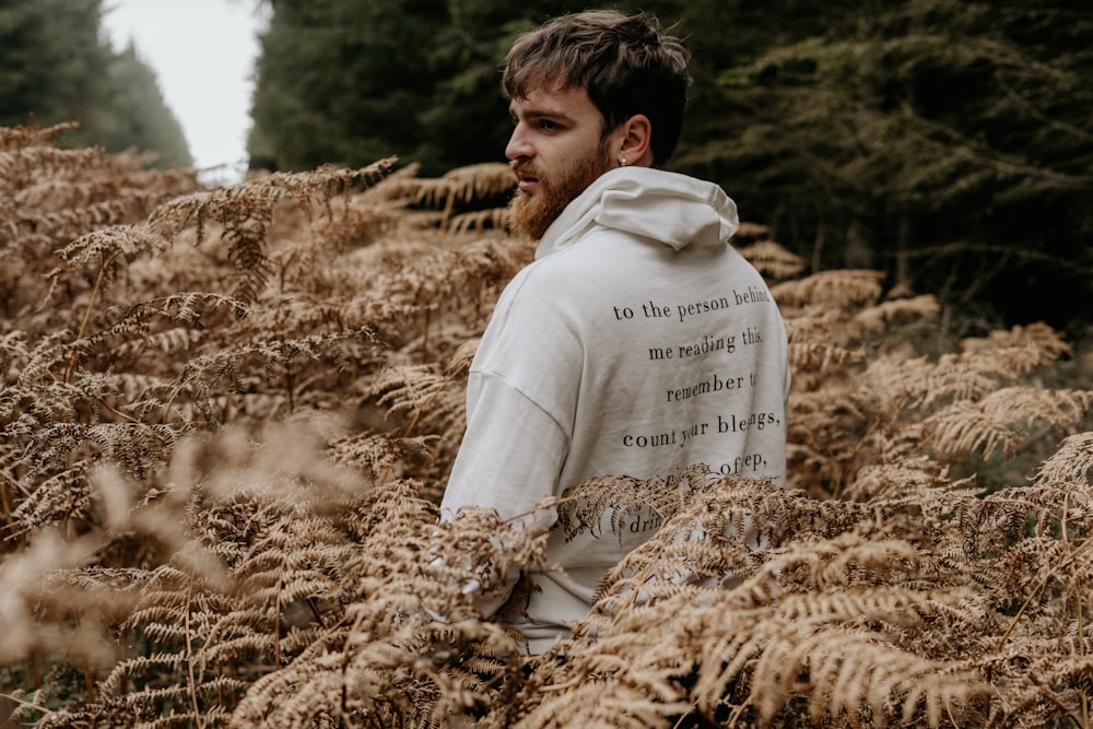 man in white hoodie sitting on brown dried grass during daytime